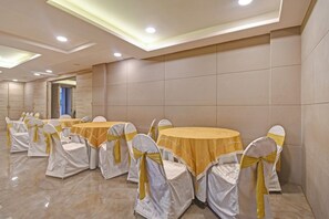 A conference room with round tables and chairs, each with a white cover and a yellow ribbon. - Super Townhouse Hotel All In One  (Barasat)
