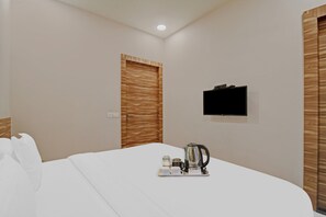 A hotel room with a bed, a television mounted on the wall, and a tray with a kettle and cups. - Super Townhouse Hotel All In One  (Barasat)