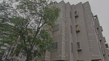 Un edificio de varios pisos con un diseño arquitectónico moderno, que incluye balcones y una entrada protegida por un portón.