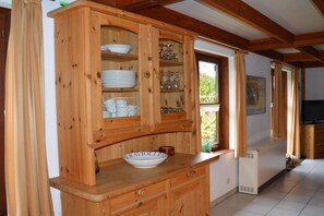 Ein Holzkabinett mit Glastüren, das Geschirr und Gläser beherbergt.