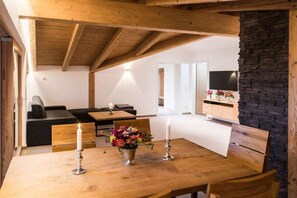A cozy living room with a wooden table, a sofa, and a stone wall. - Holiday apartment in Fischen-Berg with Wi-Fi (Fischen- Berg)