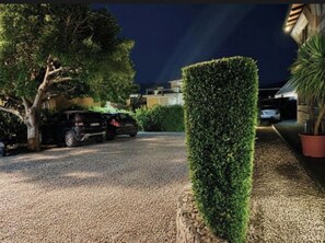 A gravel driveway leading to a parked car, a well-maintained hedge, and a building in the background. - Elgiò (Taormina)