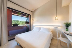 Habitación de hotel moderna con una cama grande, un escritorio y vistas a un paisaje verde.