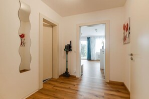 Ein Flur mit Holzboden, einem Staubsauger und einer Tür zu einem anderen Raum.