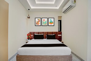 A hotel room with a bed, a nightstand, a vase of flowers, and three framed artworks on the wall. - Townhouse Indore Ring Road (Indore)