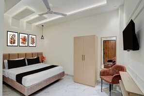 A modern bedroom with a bed, a wardrobe, a desk, a chair, a ceiling fan, and artwork on the wall. - Townhouse Indore Ring Road (Indore)