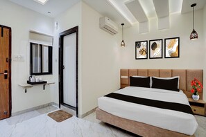 A hotel room with a bed, bedside table, wall-mounted air conditioning unit, and framed artwork. - Townhouse Indore Ring Road (Indore)