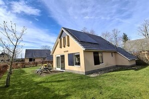 A single-story house with a sloped roof, a patio with a table and chairs, and a small garden area. - Holiday home in Sondel with swimming pool (Sondel)