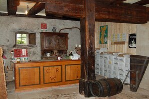 A rustic bar area with wooden cabinets, a counter with 'CRW' branding, and a wooden barrel. - Holiday apartment with 2 bedrooms (Andlau)