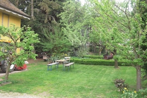 A well-maintained garden with a lawn, a table with chairs, and a yellow building in the background. - Holiday apartment with 2 bedrooms (Andlau)