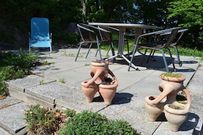 An outdoor seating area with a metal table and chairs, surrounded by terracotta planters. - Gutmann's cellar house (Fehring)