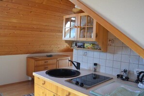 A kitchen with wooden cabinets, a sink, a stove, and a tiled backsplash. - Gutmann's cellar house (Fehring)