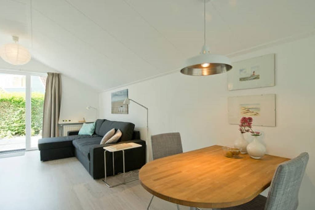 Ein modernes Wohnzimmer mit einem Holzesstisch, einer Couch und einem großen Fenster.
