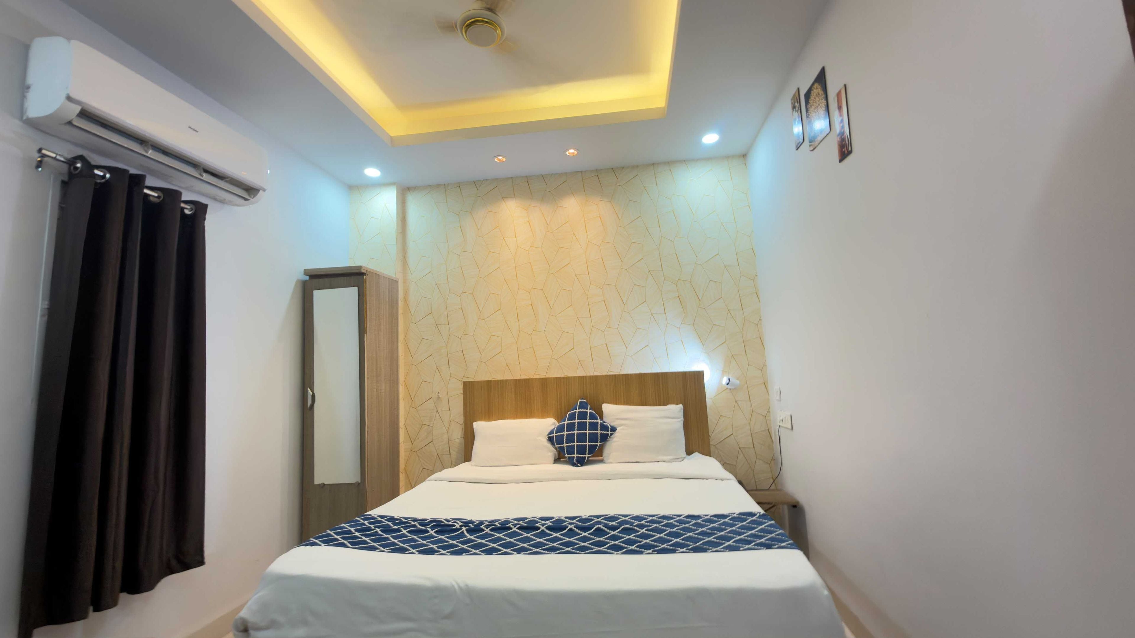 Habitación de hotel con cama, armario, aire acondicionado y una lámpara de techo.