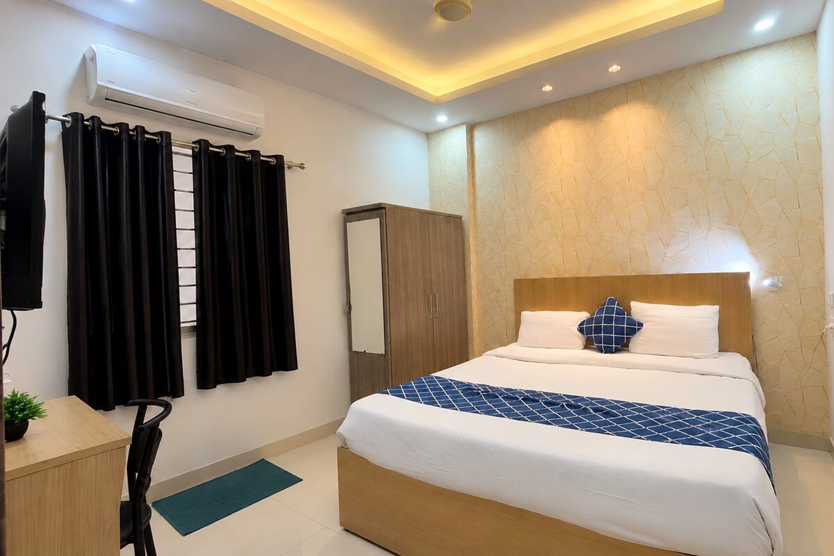 A hotel room with a bed, a wardrobe, a desk, and a curtain.
