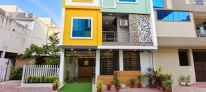 A multi-story residential building with a reception area, potted plants, and a white picket fence. - Collection O Vijay Nagar Square Indore (Indore)