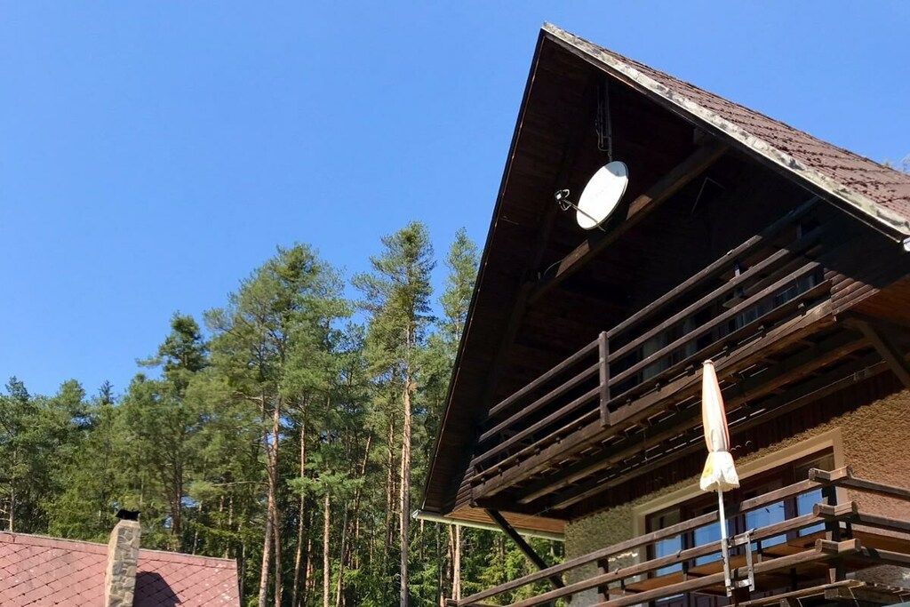 A wooden cabin with a sloped roof and a satellite dish.
