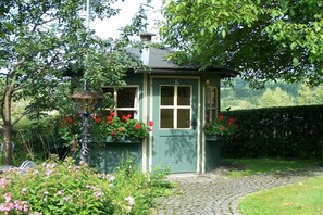 Una casa pintoresca con una puerta verde, un cartel con el número 15 y un jardín con flores y un sendero de adoquines.