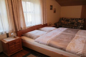 Un dormitorio con una cama de madera, una mesita de noche, una lámpara y un sofá estampado.