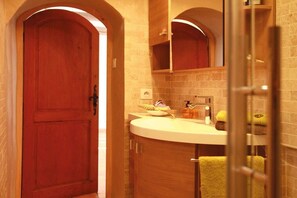 Une salle de bain avec une porte en bois, un lavabo avec des articles de toilette et un miroir au-dessus.