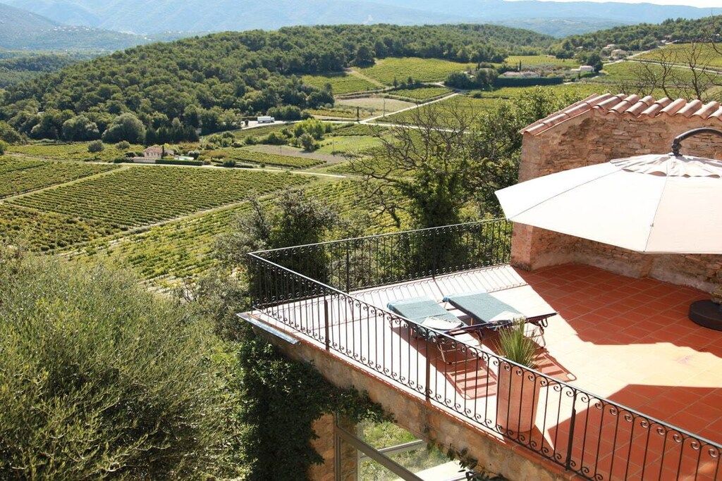 A terrace with a view of vineyards and a stone building.