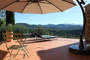 A patio with a table and chairs, a large umbrella, and a view of mountains. - ||-------------------------Balcon du Ventoux---------------------------|| (Faucon)