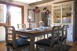 A dining area with a wooden table and chairs, pendant lights, and a cabinet with dishes. - ||-------------------------Balcon du Ventoux---------------------------|| (Faucon)