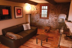 A cozy living room with a brown leather sofa, a wooden coffee table, and a rustic brick floor. - ||-------------------------Balcon du Ventoux---------------------------|| (Faucon)