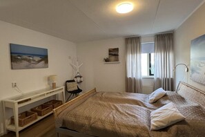 Une chambre à coucher avec un lit, une table de chevet, une lampe et une fenêtre avec des rideaux.