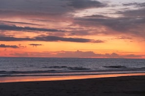 Une plage avec des vagues et un coucher de soleil.