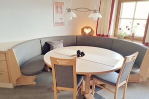 A dining area with a round table, four chairs, a bench, and a wall-mounted light fixture. - Holiday apartment with 1 bedroom (Hippach)