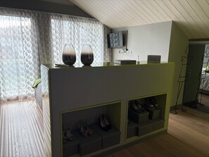 A room with a wooden floor, a TV mounted on the wall, a sofa, and a shoe display unit. - Architect-designed home with a heated pool, just a stone's throw from Geneva and the ski slopes (Présilly)