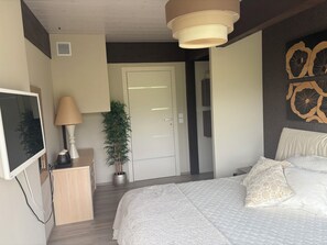 A bedroom with a bed, a desk, a TV, a lamp, and a potted plant. - Architect-designed home with a heated pool, just a stone's throw from Geneva and the ski slopes (Présilly)