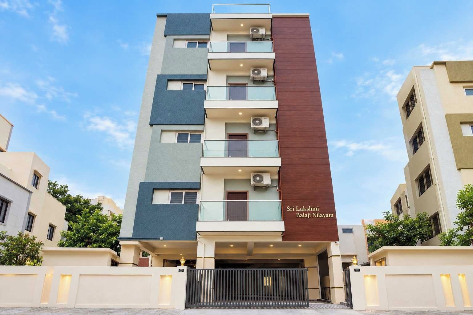 Un edificio residencial de varios pisos con balcones, unidades de aire acondicionado y una entrada protegida por una reja.