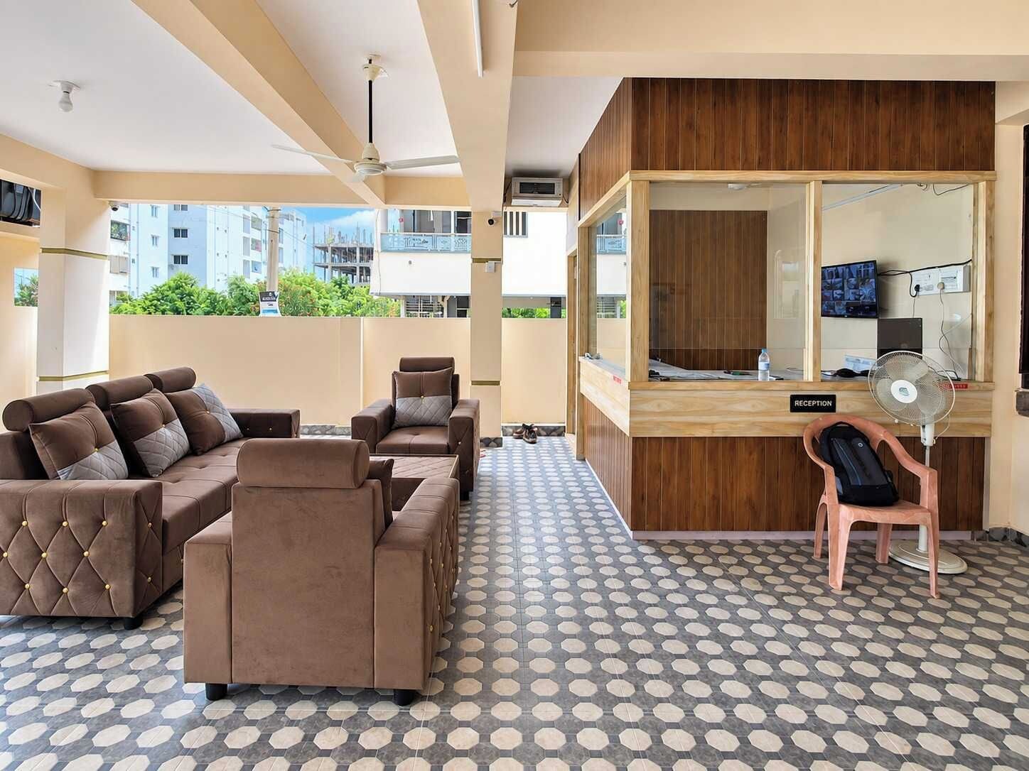 Un área de recepción con mostrador, una zona de estar con sofás y un piso con diseño.
