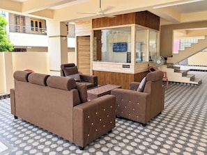 A reception area with a reception desk, seating area with sofas, a television, and a staircase. - Hotel O Tirumala Hill View Tirupati (Tirupati)