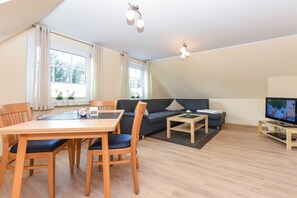 A modern living room with a dining table, sofa, and TV. - Holiday apartment with 2 bedrooms (Werdum\/Nordwerdum)