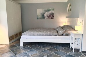 A bedroom with a bed, a nightstand, a wall-mounted lamp, and a door. - 3 "Sea Lavender" in Letj Reethüs (Norddorf)