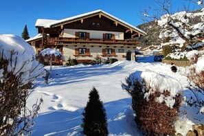 Ein Chalet-ähnliches Gebäude mit schneebedecktem Dach, Holzbalkonen und blauem Himmel.