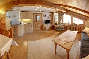 A cozy, open-plan living space with a kitchen, dining area, and seating area. - Guesthouse on the Großwaldbach (Inzell)