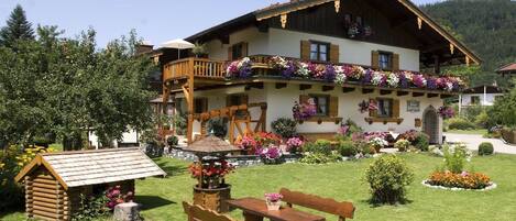 Un chalet tradicional con balcón decorado con flores, un banco de madera y un pequeño jardín.