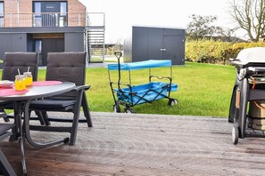 Un patio exterior con una mesa y sillas, un cortacésped azul y una parrilla de barbacoa.