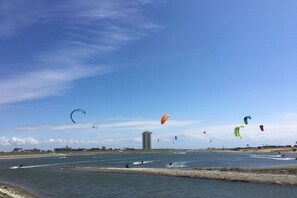 A coastal area with multiple kitesurfing activities, a body of water, and a distant building. - Holiday apartment in Büsum with swimming pool (Büsum)