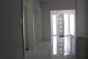 A hallway with a shiny tiled floor, white walls, and doors leading to other rooms. - Holiday apartment in Waren with swimming pool (Waren)