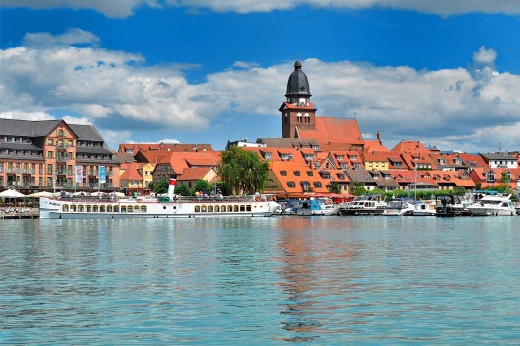 A waterfront cityscape with historic buildings, a prominent tower, and a river with boats.