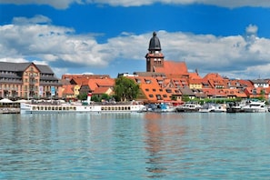 A waterfront cityscape with historic buildings, a prominent tower, and a river with boats. - Holiday apartment in Waren with swimming pool (Waren)