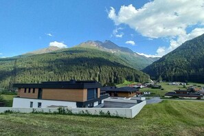 Un bâtiment moderne doté d’un toit plat, entouré d’un paysage rural avec des montagnes et un ciel dégagé.