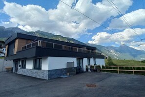 A modern building with a flat roof, large windows, and a balcony overlooking a mountainous landscape. - Apart Sopherl 5-8 PAX (Pettneu)