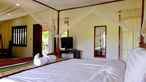 Een slaapkamer met een bed, een televisie, een spiegel en een raam met gordijnen.