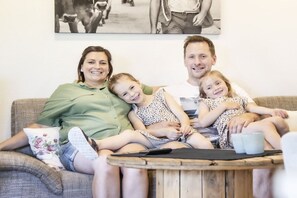 A family of four on a couch with a wooden coffee table in front. - Holiday apartment in Egg with swimming pool (Egg)